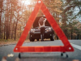 Auto assistance and insurance, troubles while traveling concept. Broken car and auto triangle on road, woman waiting for help