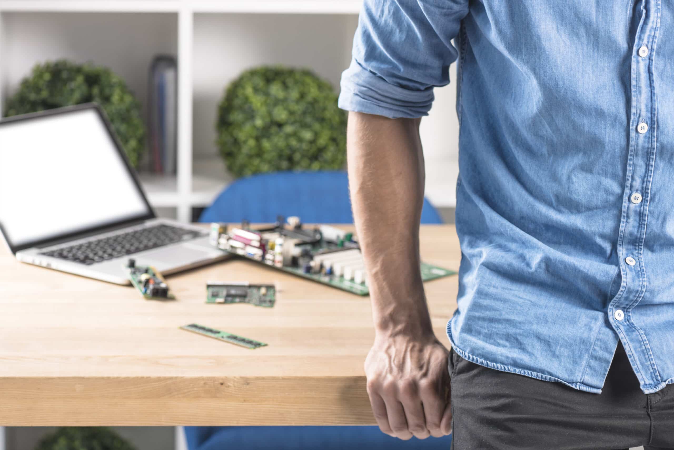 close-up-male-technician-leaning-edge-table-with-laptop-hardware-equipment-s