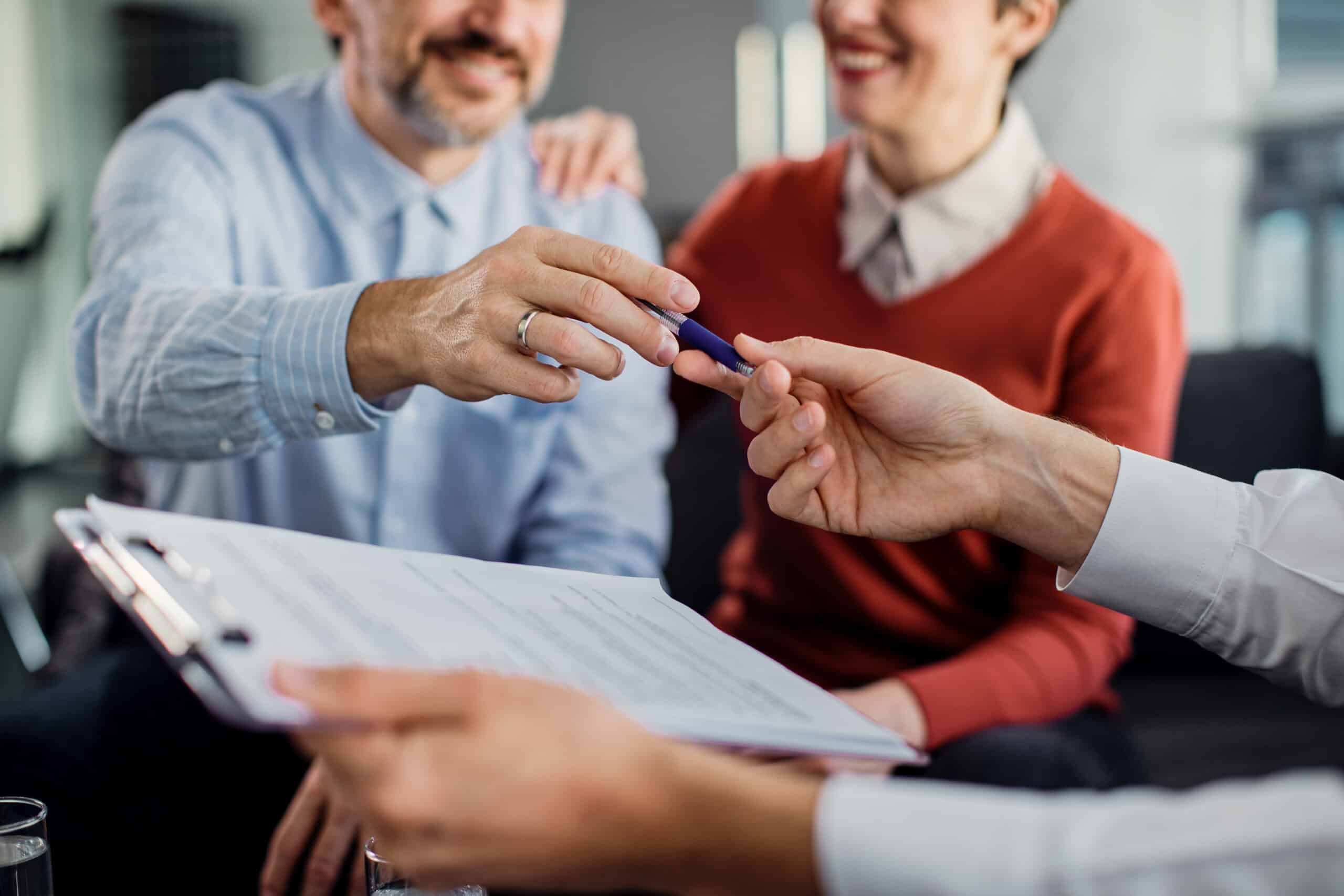 Close-up of a couple signing an agreement with insurance agent i